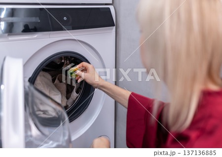 House hold. Female person using washing machine at home focusing on daily chores clean textiles and contemporary interior environment. House hold. Female person using washing machine at home focusing on daily chores clean textiles and contemporary interior environment. 137136885