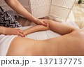 Therapist gently massages a woman arm and elbow on a white massage table, soft warm light highlighting smooth skin and creating a calm, restorative spa wellness atmosphere. 137137775