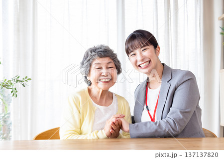 高齢者に寄り添う女性スタッフと笑顔のシニア女性 137137820