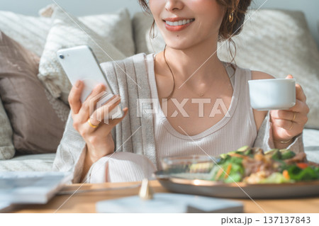 朝食,ランチを食べながらスマホを見る女性(アプリ,SNS) 137137843
