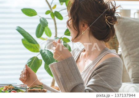 リビングテーブルで食事をするおしゃれな若いアジア人女性 リビングテーブルで食事をするおしゃれな若いアジア人女性 137137944