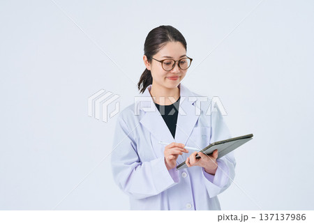 タブレットPCを使う白衣の女性 タブレットPCを使う白衣の女性 137137986