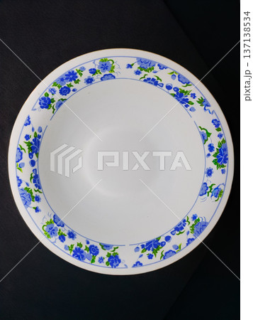 White plate with blue flowers on a black background. Top view White plate with blue flowers on a black background. Top view 137138534