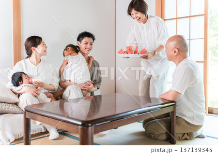 夏休みに里帰りした息子夫婦をスイカでもてなす両親 137139345