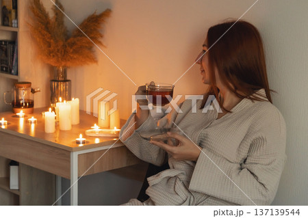 Woman enjoying warm tea by candlelight, embracing self-care and mindfulness in a cozy, tranquil setting, home spa wellness Woman enjoying warm tea by candlelight, embracing self-care and mindfulness in a cozy, tranquil setting, home spa wellness 137139544