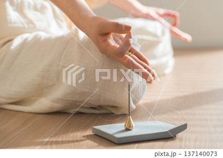 部屋で焚くお香とヨガで瞑想する女性の手元 137140073