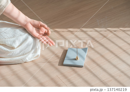 部屋で焚くお香とヨガで瞑想する女性の手元 部屋で焚くお香とヨガで瞑想する女性の手元 137140219
