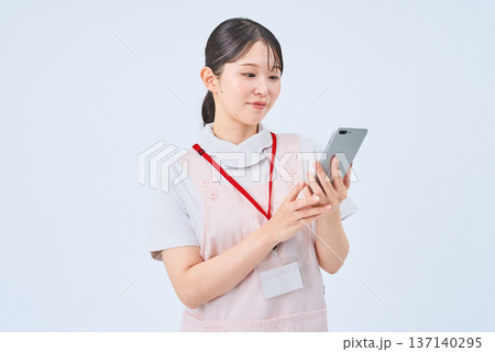 白衣とエプロンを着てデジタル機器を持つ若い女性 白衣とエプロンを着てデジタル機器を持つ若い女性 137140295