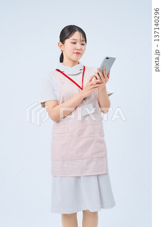 白衣とエプロンを着てデジタル機器を持つ若い女性 白衣とエプロンを着てデジタル機器を持つ若い女性 137140296
