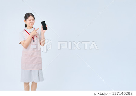 白衣とエプロンを着てデジタル機器を持つ若い女性 白衣とエプロンを着てデジタル機器を持つ若い女性 137140298