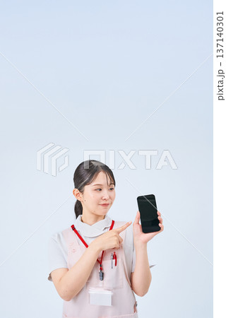 白衣とエプロンを着てデジタル機器を持つ若い女性 白衣とエプロンを着てデジタル機器を持つ若い女性 137140301