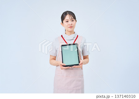 白衣とエプロンを着てデジタル機器を持つ若い女性 白衣とエプロンを着てデジタル機器を持つ若い女性 137140310