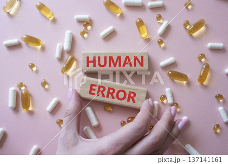 Human Error symbol. Concept word Human Error on wooden blocks. Beautiful pink background with pills. Doctor Hand. Medicine and Human Error concept. Copy space Human Error symbol. Concept word Human Error on wooden blocks. Beautiful pink background with pills. Doctor Hand. Medicine and Human Error concept. Copy space 137141161