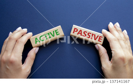 Active or Passive symbol. Concept word Active or Passive on wooden blocks. Businessman hand. Beautiful deep blue background. Business and Active or Passive concept. Copy space 137141167