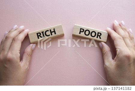 Rich vs Poor symbol. Concept word Rich vs Poor on wooden blocks. Businessman hand. Beautiful pink background. Business and Rich vs Poor concept. Copy space Rich vs Poor symbol. Concept word Rich vs Poor on wooden blocks. Businessman hand. Beautiful pink background. Business and Rich vs Poor concept. Copy space 137141182