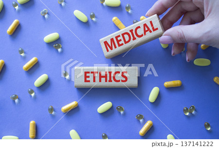 Medical Ethics symbol. Concept word Medical Ethics on wooden blocks. Doctor Hand. Beautiful purple background with pills. Medicine and Medical Ethics concept. Copy space Medical Ethics symbol. Concept word Medical Ethics on wooden blocks. Doctor Hand. Beautiful purple background with pills. Medicine and Medical Ethics concept. Copy space 137141222