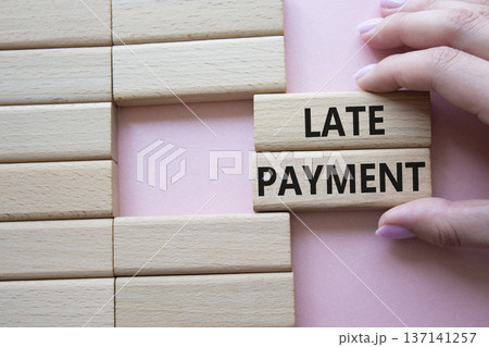 Late payment symbol. Concept word Late payment on wooden blocks. Beautiful pink background. Businessman hand. Business and Late payment concept. Copy space 137141257
