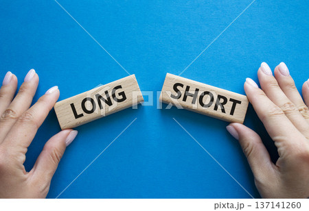 Short vs Long symbol. Concept word Short vs Long on wooden blocks. Businessman hand. Beautiful blue background. Business and Short vs Long concept. Copy space 137141260