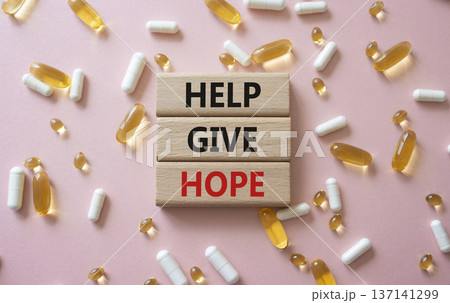 Help Give Hope symbol. Concept word Help Give Hope on wooden blocks. Beautiful pink background with pills. Medicine and Help Give Hope concept. Copy space 137141299