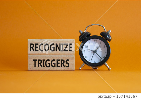 Recognize triggers symbol. Concept words Recognize triggers on wooden blocks. Beautiful orange background with alarm clock. Business and Recognize triggers concept. Copy space. 137141367