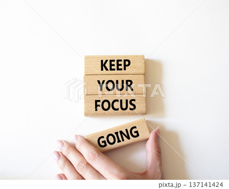Focus symbol. Concept words Keep Your Focus Going on wooden blocks. Beautiful bright white background. Businessman hand. Business and Keep Your Focus Going concept. Copy space. 137141424