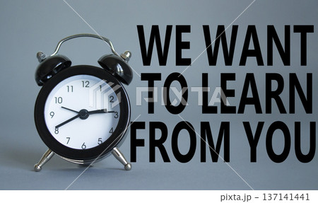 We want to learn from you symbol. Wooden blocks with words We want to learn from you. Beautiful grey background with alarm clock. Business and We want to learn from you. Copy space. 137141441