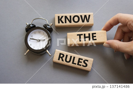 Know the rules symbol. Wooden blocks with words Know the rules. Businessman hand. Beautiful grey background with alarm clock. Business and Know the rules concept. Copy space. 137141486