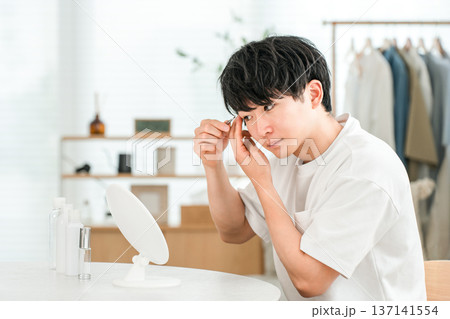 鏡を見ながら眉バサミで眉毛を整える若いアジア人男性 鏡を見ながら眉バサミで眉毛を整える若いアジア人男性 137141554