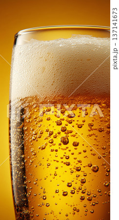 Fizzy beer glass with foam in closeup on warm golden background, concept of refreshment and celebration Fizzy beer glass with foam in closeup on warm golden background, concept of refreshment and celebration 137141673