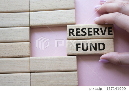 Reserve Fund symbol. Concept word Reserve Fund on wooden blocks. Beautiful pink background. Businessman hand. Business and Reserve Fund concept. Copy space Reserve Fund symbol. Concept word Reserve Fund on wooden blocks. Beautiful pink background. Businessman hand. Business and Reserve Fund concept. Copy space 137141990