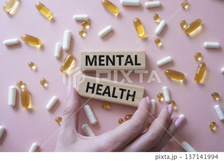 Mental Health symbol. Concept word Mental Health on wooden blocks. Doctor Hand. Beautiful pink background with pills. Medicine and Mental Health concept. Copy space 137141994