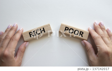 Rich vs Poor symbol. Concept word Rich vs Poor on wooden blocks. Businessman hand. Beautiful white background. Business and Rich vs Poor concept. Copy space Rich vs Poor symbol. Concept word Rich vs Poor on wooden blocks. Businessman hand. Beautiful white background. Business and Rich vs Poor concept. Copy space 137142017