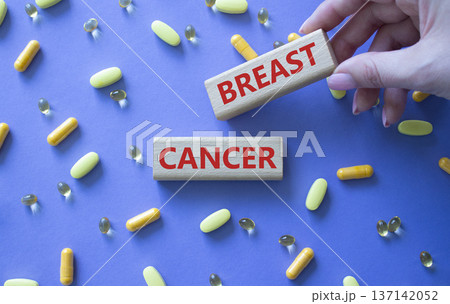 Breast cancer symbol. Wooden blocks with words Breast cancer. Beautiful purple background with pills. Doctor hand. Medicine and Breast cancer concept. Copy space. 137142052