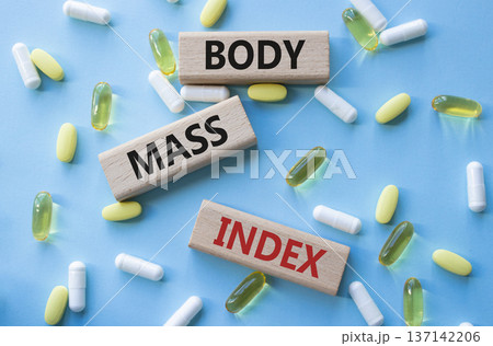 Body Mass Index symbol. Concept word Body Mass Index on wooden blocks. Beautiful blue background with pills. Medicine and Body Mass Index concept. Copy space Body Mass Index symbol. Concept word Body Mass Index on wooden blocks. Beautiful blue background with pills. Medicine and Body Mass Index concept. Copy space 137142206