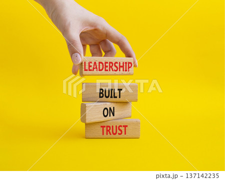 LEADERSHIP symbol. Wooden blocks with words LEADERSHIP BUILT ON TRUST. Businessman hand. Beautiful yellow background. Business and LEADERSHIP concept. Copy space 137142235