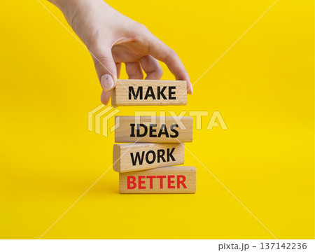 MAKE IDEAS WORK BETTER symbol. Wooden blocks with words MAKE IDEAS WORK BETTER. Businessman hand. Beautiful yellow background. Business concept. Copy space 137142236