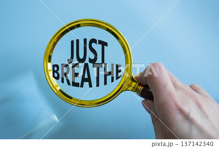 Just Breathe symbol. Magnifying glass with words Just Breathe. Beautiful blue background. Businessman hand. Business and Just Breathe concept. Copy space. 137142340
