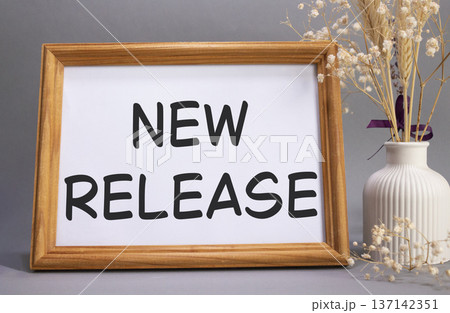 New Release symbol. Concept words New Release on beautiful wooden picture frame. Beautiful grey background with flower vase. Business and New Release concept. Copy space. 137142351