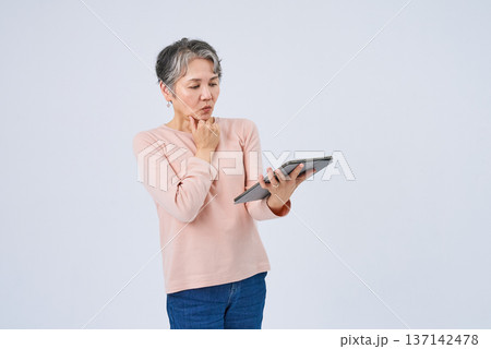 デジタルデバイスを手にするシニア女性 デジタルデバイスを手にするシニア女性 137142478