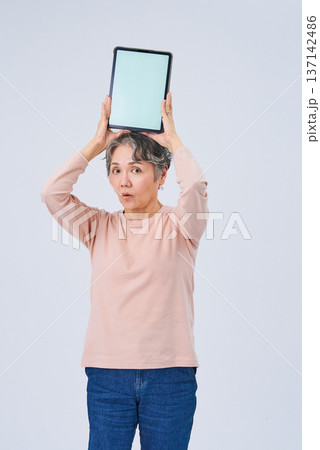 デジタルデバイスを手にするシニア女性 デジタルデバイスを手にするシニア女性 137142486