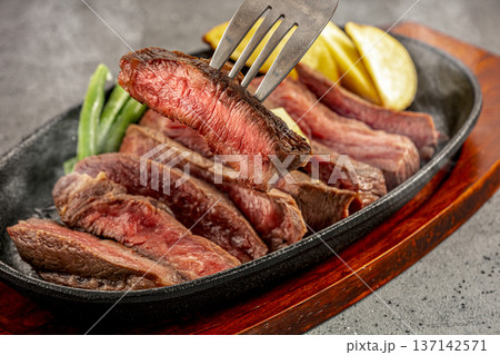 鉄板皿で提供される国産牛のステーキ 137142571