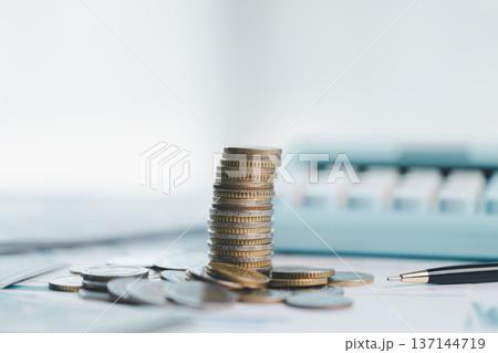 Stacks of coins on financial report with charts, blurred calculator in background, symbolizing savings, investment growth, budgeting and wealth management for business planning strategy. saving Stacks of coins on financial report with charts, blurred calculator in background, symbolizing savings, investment growth, budgeting and wealth management for business planning strategy. saving 137144719