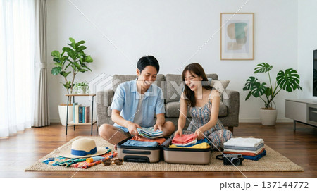 リビングで夏の旅行準備を楽しむ笑顔の夫婦 137144772