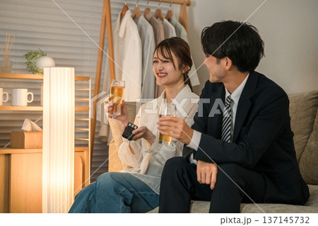 夜,帰宅後にソファに座りながらビールを飲む若いアジア人夫婦,カップル 夜,帰宅後にソファに座りながらビールを飲む若いアジア人夫婦,カップル 137145732