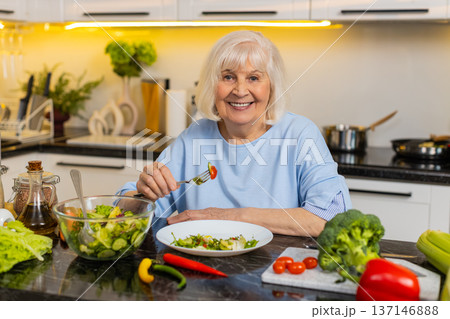 Senior old woman enjoying vegetable salad at home kitchen for healthy diet weight control nutrition Senior old woman enjoying vegetable salad at home kitchen for healthy diet weight control nutrition 137146888