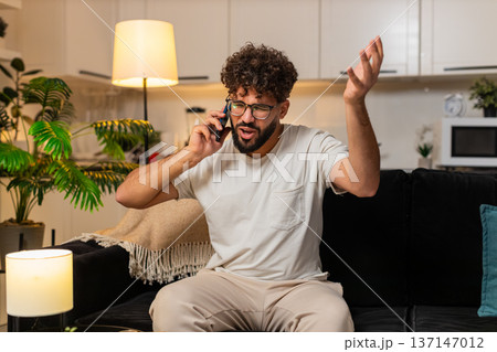 Arabian man argues on smartphone with robocall scam declines pushy offer frustrated at night indoors 137147012