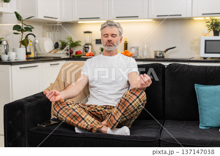 Middle-aged man sets meditation timer on smartphone sits straight breathes prepares for calm session 137147038