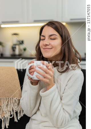 Young woman drinks herbal tea holds warm cup takes slow sip relax enjoy simple leisure mindfully sip 137147055
