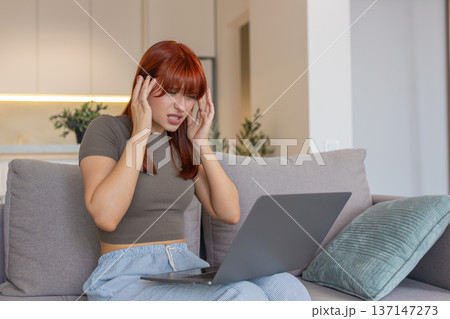 Young woman with laptop rubs temples headache pause closes eyes tired takes break for relief needed 137147273