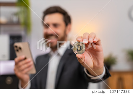 Middle-aged businessman cheers at Bitcoin chart on smartphone shouting wow about investment success 137147388
